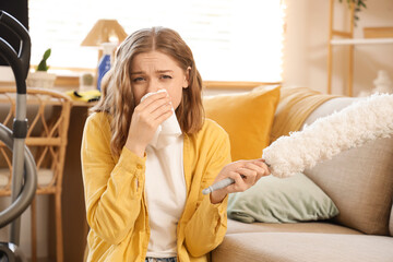 Young woman suffering from dust allergy while cleaning flat