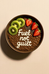 Chocolate Oatmeal Bowl with Kiwi, Strawberries, Chia Seeds and White Icing Text "Fuel not guilt" – Healthy Breakfast with Funny Quote in Clean Editorial Food Photography Style