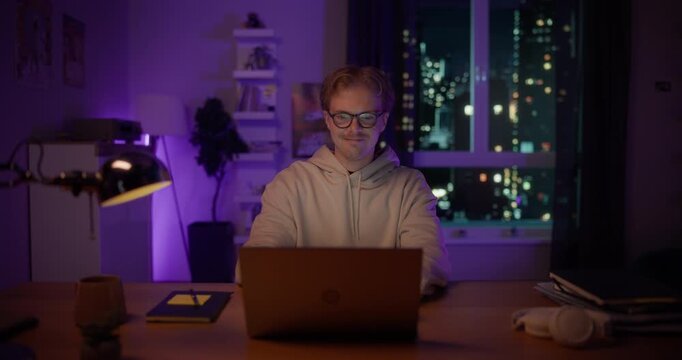 Close Up of a Young Man Opening Up a Laptop and Starting to Work. Male in Glasses Sitting Behind a Table at Home in a Living Room, Using Computer. Dynamic Robot Camera Footage