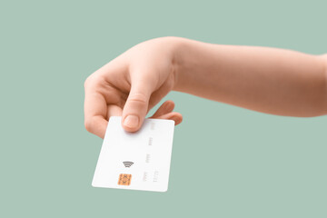 Female hand with credit card on light turquoise background, closeup