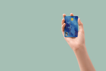 Female hand with credit card on light turquoise background