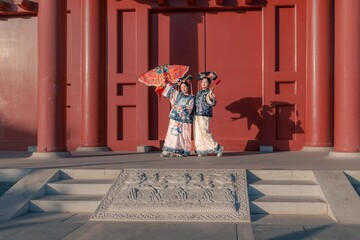 Two young Asian women with colorful umbrellas in traditional clothing.