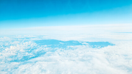 View through plane window showing high altitude clouds and endless blue sky