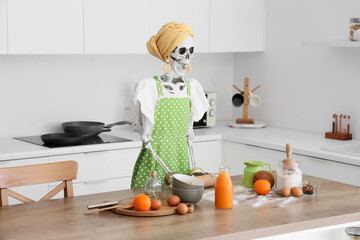 Human skeleton model dressed as housewife with rolling pin at table in kitchen