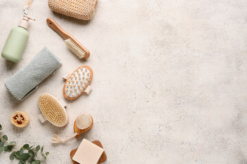 Composition with massage body brushes, towel and bottle of cosmetic product on white grunge background