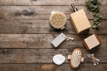 Composition with massage body brushes, soap bar, bottle of cosmetic product and green twig on wooden background