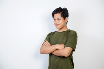 Portrait of a confident young Asian man, wearing a green casual shirt, standing against a clean...