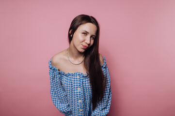 portrait of young thoughtful young woman with a soft smile on pink background