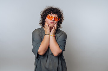 portrait of young surprised curly-haired woman portrays curiosity and thoughtfulness while making a...