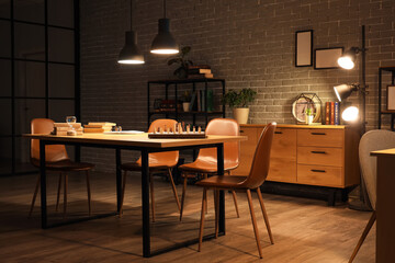 Interior of dark room with bookshelf, table and glowing lamps at night