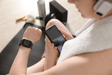 Woman checking fitness tracker during training indoors, closeup