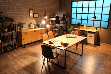 Interior of dark room with bookshelves, tables and glowing lamps at night