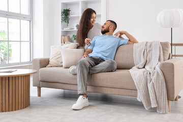 Obraz premium Young couple with key from their new house sitting on sofa in room