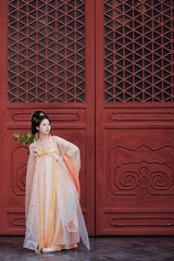 Naklejka premium Young Asian woman in traditional clothing near red door.