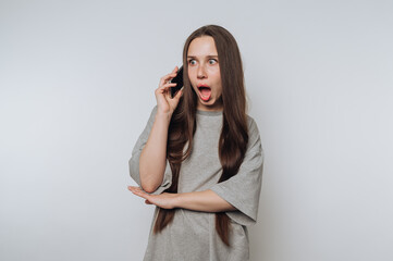 portrait of young woman reacts with surprise on a phone call, showcasing a blend of emotion and...