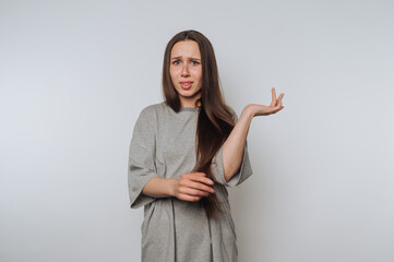portrait of young woman's discontent as she raises her hand in a questioning gesture on light...