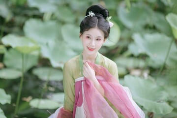 Elegant young woman in a serene lotus pond setting.