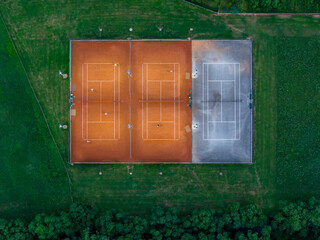 Top-down tennis court image showing dynamic match moments amid lush countryside