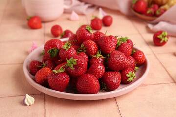 Plate with sweet ripe strawberries on beige tile background