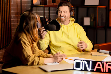 Couple of radio presenters recording at table in studio