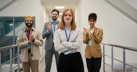 Red-haired young businesswoman crosses arms in corridor