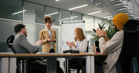 Businesswoman holds presentation while team sits at table