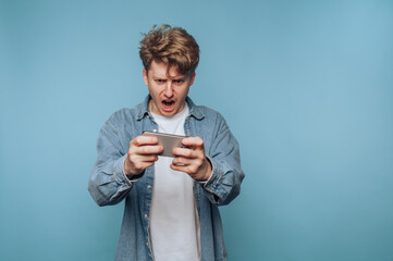 portrait of young man is frustrated while looking at his smartphone as he reacts strongly on light...