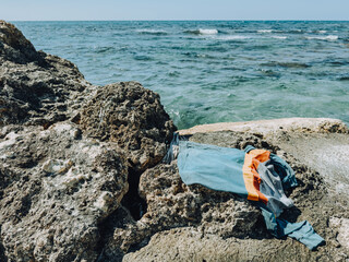 Abandoned clothes on rocky coast by the sea, raising concerns of drowning or lost swimmer