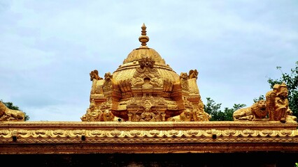 Golden Vimana, tower, gopuram of a South Indian Temple gleams under an overcast sky, adorned with...