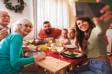 Multi-generation family taking selfies while having Christmas dinner at home