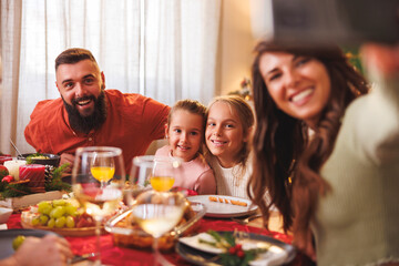Young family taking selfies while having Christmas dinner at home