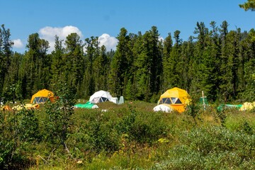 Mountain landscape. A tourist tent camp in the middle of a mountain forest. Ergaki Nature Park