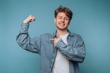 portrait of young man confidently flexes his muscles, exuding strength and positivity on light blue...
