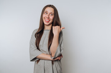 portrait of young smiling woman with long hair points towards something off-camera on light...