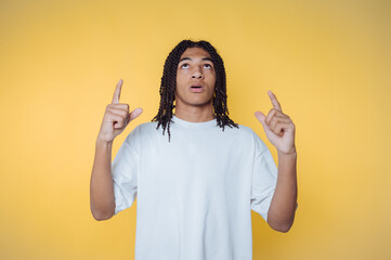 portrait of young man looking upwards and pointing as if unveiling a new idea, radiating curiosity...