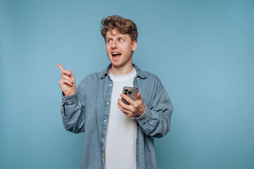 portrait of young man expresses a bright idea while engaging with his smartphone, pointing lively...