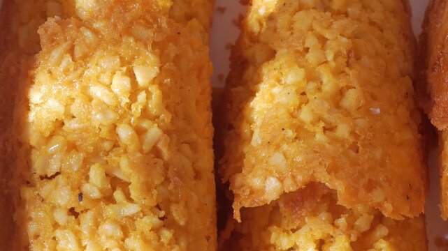 Detailed pan right of crispy almond Tejas sweets under direct sunlight, revealing texture and color.