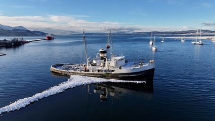 Fototapeta premium Saint Christopher Boat In Ushuaia Tierra Del Fuego Argentina. Aerial View Of A Bustling Downtown Cityscape With Modern Buildings. Nature Tourism Icon Snow Covered Forest Trees.