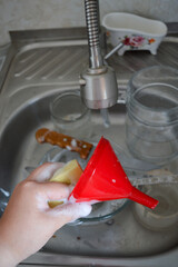hand holds foamy sponge while washing dishes in kitchen sink with dirty bowl and utensils cleaning...