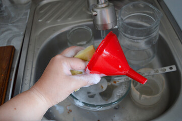 hand holds foamy sponge while washing dishes in kitchen sink with dirty bowl and utensils cleaning...