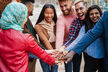 Young multiracial people stacking hands outdoor - Happy students friends celebrating together - Generation z and support concept - Main focus on hands