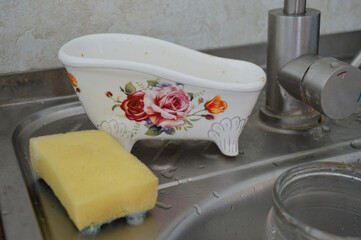 yellow sponge and decorative floral ceramic bowl placed on wet kitchen sink near faucet kitchen...