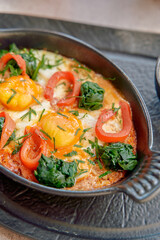 Deliciously baked eggs with fresh spinach, vibrant tomatoes, and fragrant herbs in a sizzling dish, perfect for brunch or a hearty meal.