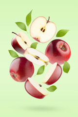 Bright red apples, green leaves levitation as swirl on pastel green background as art composition,...