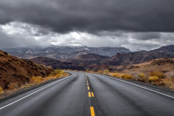 Naklejka premium Empty highway winds through a rugged, autumnal landscape under a stormy sky