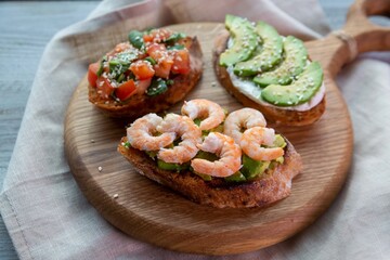 Bruschetta with avocado, shrimp, tomatoes, guacamole, cream cheese and herbs. Healthy eating.