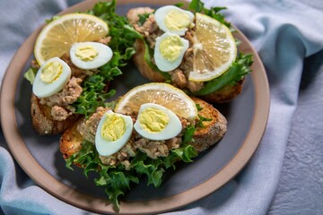 Bruschetta with cod liver, quail eggs, lemon and herbs. Italian Cuisine. Healthy eating.