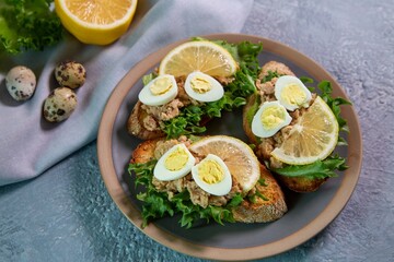Bruschetta with cod liver, quail eggs, lemon and herbs. Italian Cuisine. Healthy eating.
