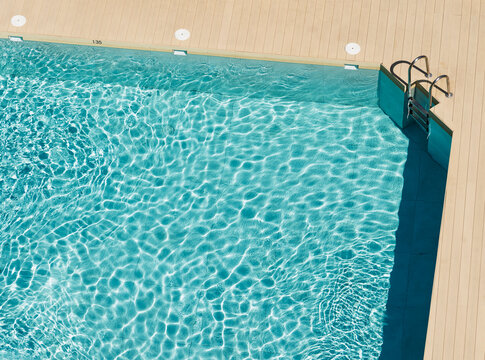 Vista desde arriba de una piscina y la escalera de acceso a pleno sol en verano	