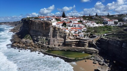 Obraz premium Azenhas Do Mar Beach In Sintra District Of Lisbon Portugal. Aerial View Of A Bustling Downtown Cityscape With Modern Buildings. Coast Horizon Seaside Summertime. Seaside Beach Panning Wide.